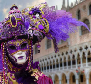 Person in aufwendig verzierter venezianischer Karnevalsmaske und violettem Kost&uuml;m vor dem Dogenpalast in Venedig.