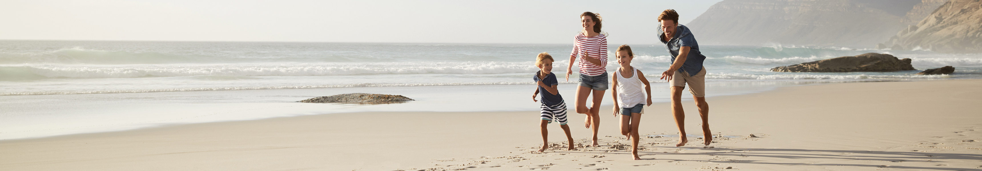 Familie l&auml;uft am Sandstrand entlang