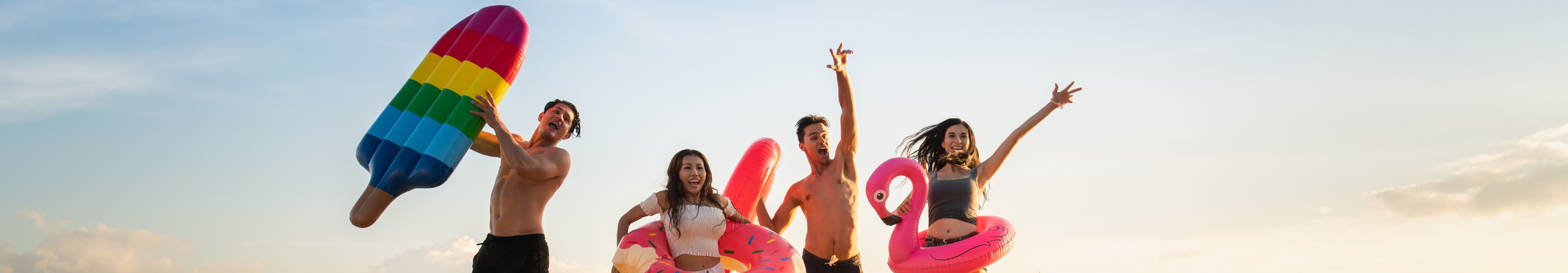 Familie mit Luftmatratzen springen am Strand in die Höhe