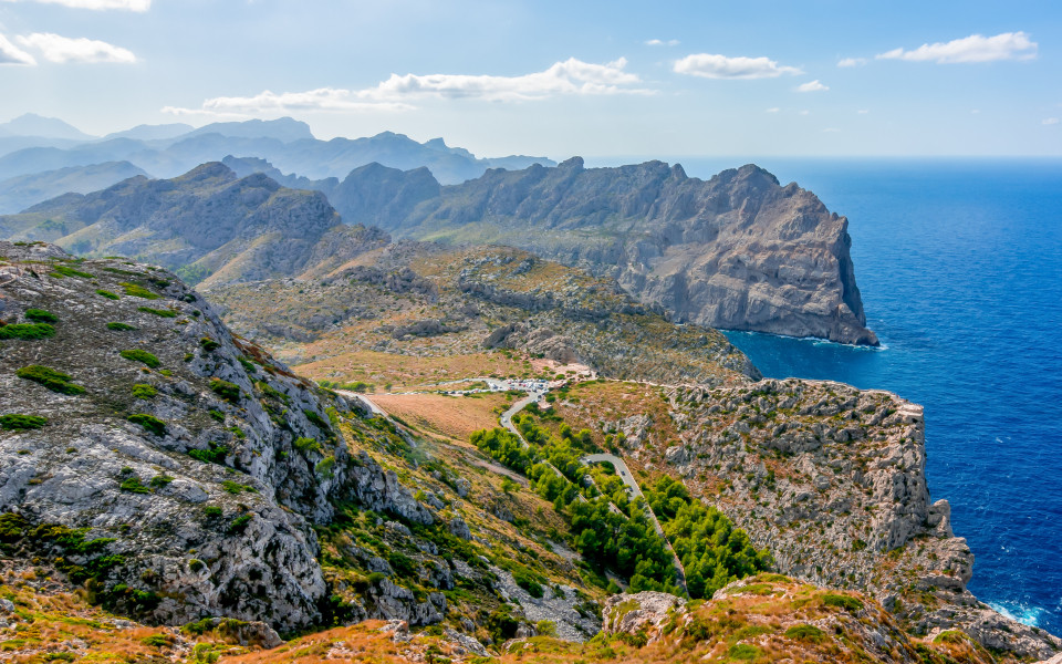 Mallorca Ausflugstipp: Berglandschaft der Serra de Tramuntana auf Mallorca mit zerkl&uuml;fteten Felsen, gr&uuml;nen T&auml;lern und spektakul&auml;rem Blick auf das tiefblaue Meer.