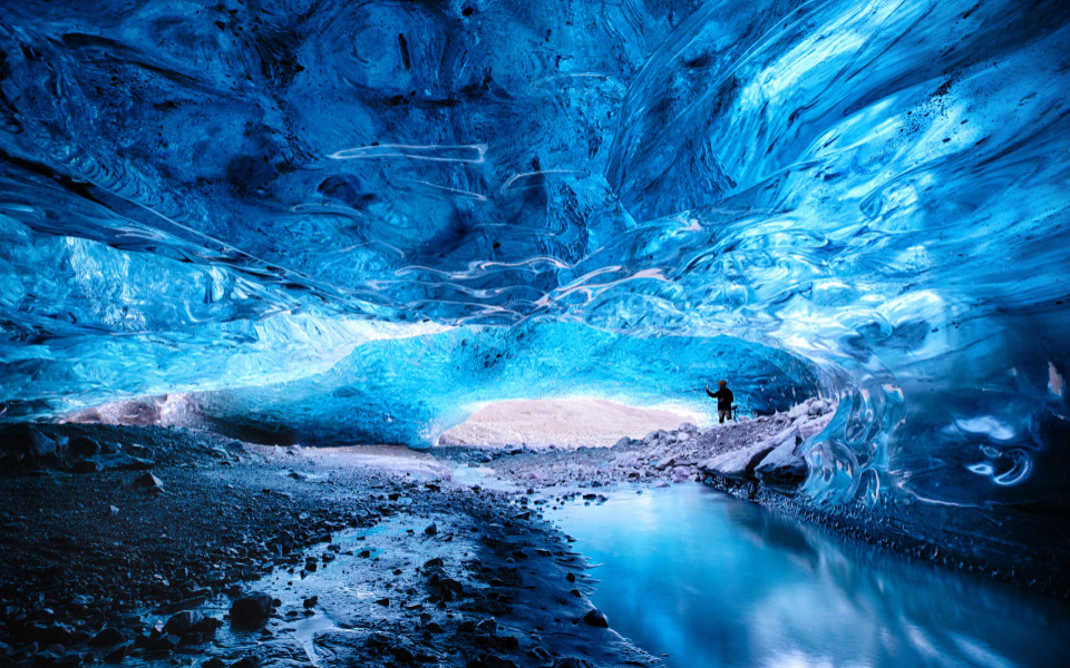 Mann macht ein Foto in der &Ouml;ffnung einer Eish&ouml;hle im Vatnaj&ouml;kull-Gletscher im S&uuml;dosten Islands