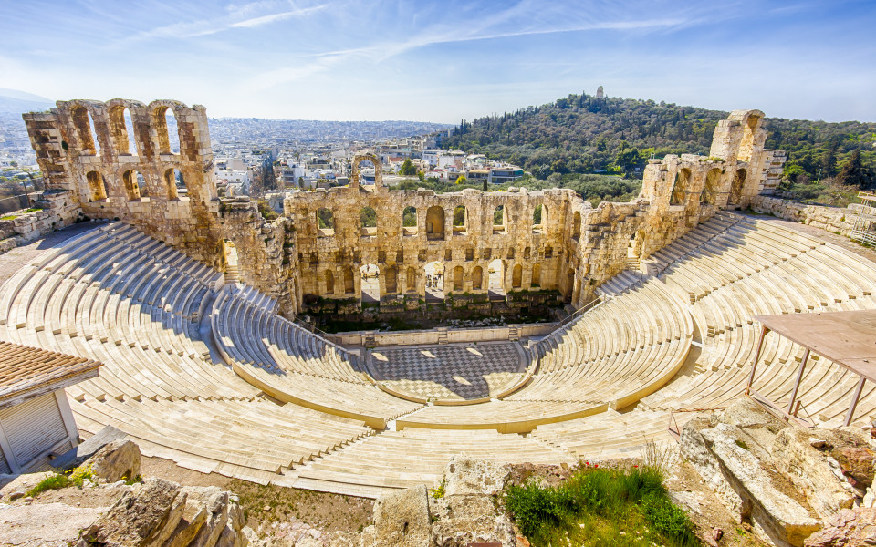Blick auf das antike Theater von Herodes Atticus in Athen, mit einer beeindruckenden r&ouml;mischen Architektur und einer weiten Aussicht auf die Stadt und die umliegenden H&uuml;gel.