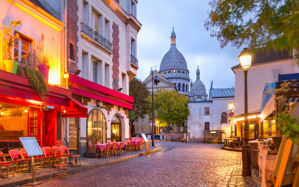 Abendstimmung im Pariser K&uuml;nstlerviertel Montmartre mit Stra&szlig;encaf&eacute;s und Blick auf die Basilika Sacr&eacute;-C&oelig;ur